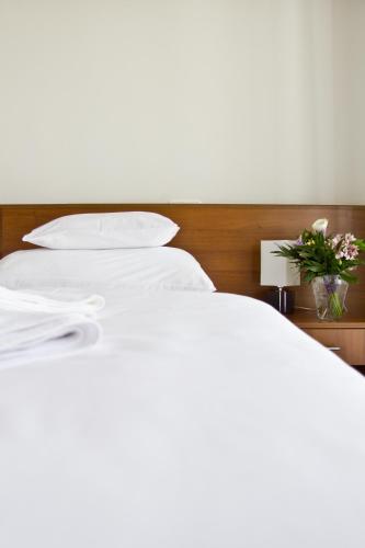 two beds with white sheets and a vase of flowers on a table at Hotel Kelep in Tokaj