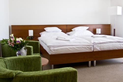 a bedroom with two beds and a chair and flowers at Hotel Kelep in Tokaj