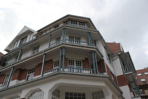 a white building with a balcony on top of it at Hotel Astel in De Haan