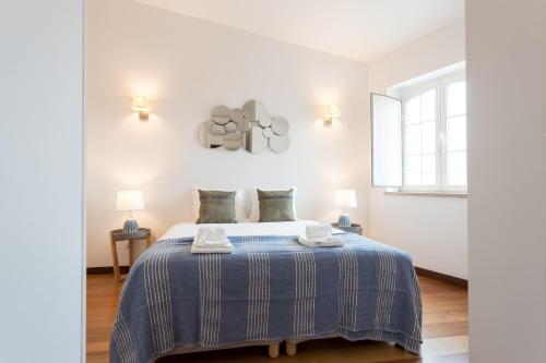 een slaapkamer met een bed met een blauw gestreepte deken bij Alfama Modern Two-Bedroom Apartment w/ River View and Parking - by LU Holidays in Lissabon