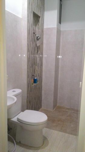 a bathroom with a white toilet and a shower at SWK 95 Hotel in Surabaya