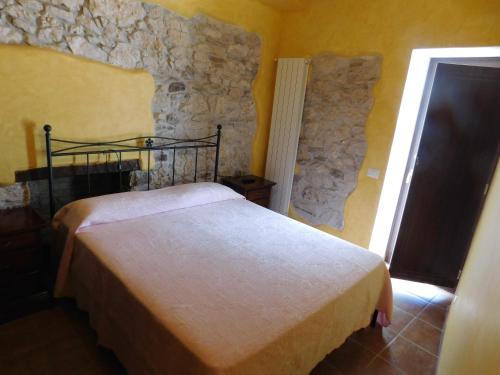 ein Schlafzimmer mit einem Bett und einer Steinmauer in der Unterkunft La Torre dell'Orologio 2.0 in Roccasicura