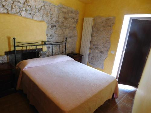 a bedroom with a bed and a stone wall at La Torre dell'Orologio 2.0 in Roccasicura