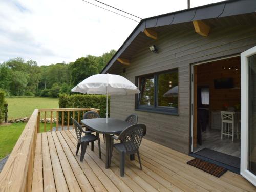 una terrazza in legno con tavolo, sedie e ombrellone di Magnificent Chalet in Ferri res Ardenne with Private Terrace a Vieuxville