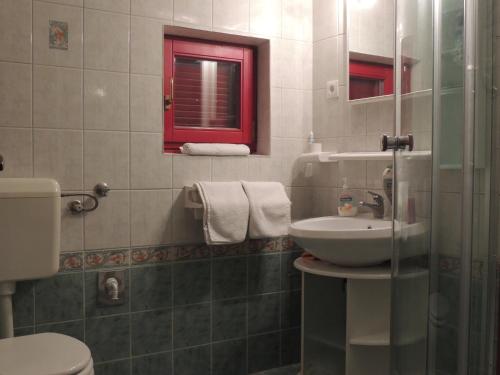 ein Bad mit einem Waschbecken, einem WC und einem Fenster in der Unterkunft Apartments Villa Aurora in Ražanac