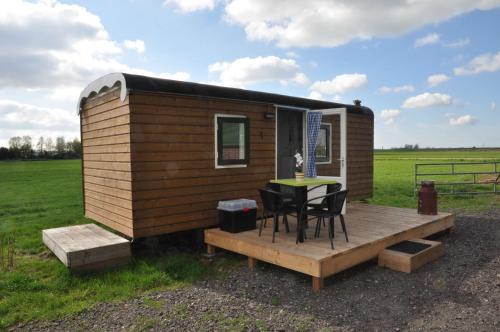 a tiny house with a table on a deck at Your Cozy Waggon at the Cows' Paradise in Amsterdam