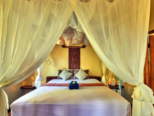 um quarto com uma grande cama branca com cortinas em Lafyu Bali em Singaraja