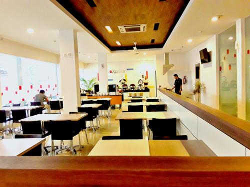 a restaurant with tables and chairs and a man standing in the background at Amaris Hotel Nagoya Hill - Batam in Nagoya