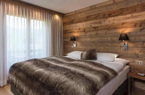 فندق سالزانو - سبا - ريستورانت في إنترلاكن: غرفة نوم بسرير كبير وجدار خشبي