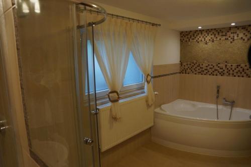 a bathroom with a shower and a tub and a window at Moris Beach Apartments in Gdańsk