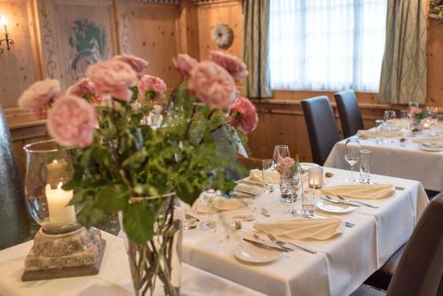 a table with a vase with pink flowers on it at SALZANO Hotel - Spa - Restaurant in Interlaken