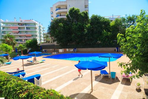 una gran piscina con sombrillas y sillas azules en UHC Alborán Apartments, en Salou