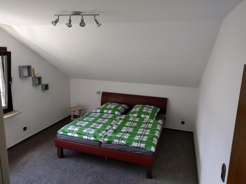 ハーヘンブルクにあるFerienwohnung Hachenburgのベッドルーム1室(緑と白の毛布付きのベッド1台付)
