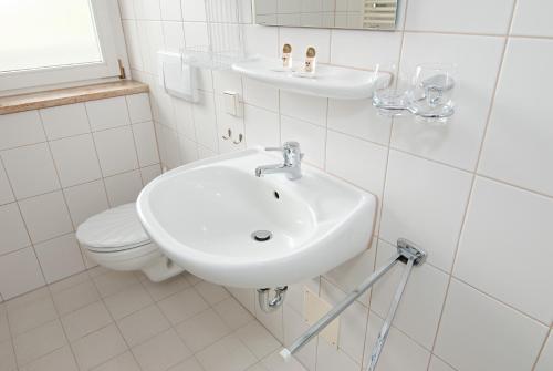 a white bathroom with a sink and a toilet at Vitalhotel Weisse Elster in Bad Elster