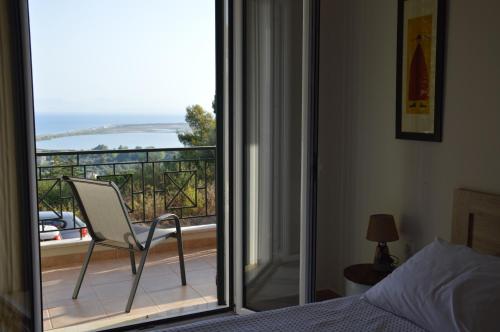 een slaapkamer met een bed en een stoel op een balkon bij Erismini in Lefkada