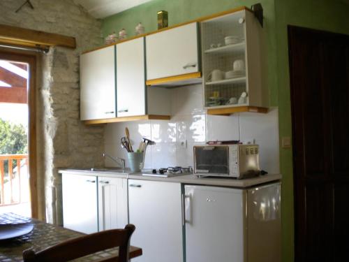 een keuken met witte kasten en een magnetron bij Au col de Cygne in Blanzac-lès-Matha