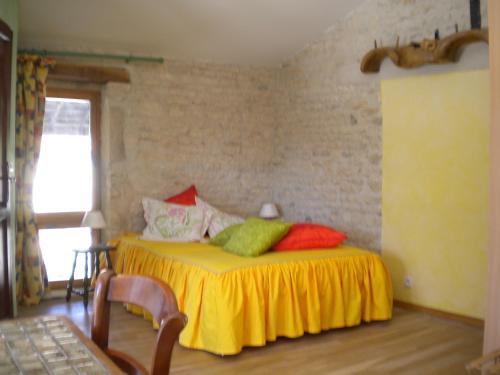 een slaapkamer met een geel bed en kleurrijke kussens bij Au col de Cygne in Blanzac-lès-Matha