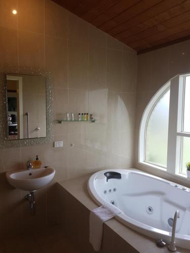a bathroom with a tub and a sink and a window at Getaway Inn Boutique Guest house in Nulkaba