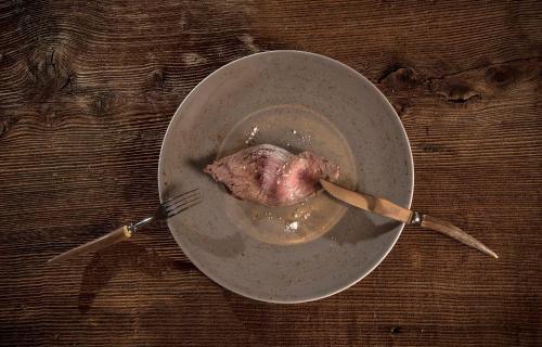 a piece of meat in a bowl with two forks at Salzano Basic Rooms Interlaken in Interlaken