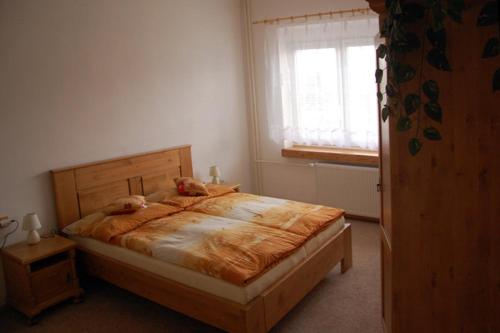 a bedroom with a wooden bed with a window at Apartman Horni Adrspach in Adršpach