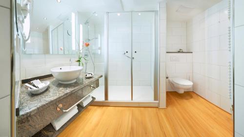 a bathroom with a shower and a sink and a toilet at Flair Hotel Adlerbad in Bad Peterstal