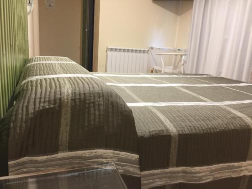 a bed with a green and white blanket on it at Hostal Santa Baia in Ribadumia