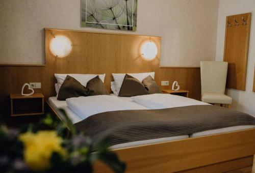 a bedroom with a large bed with two tables and a chair at Landgasthof Linkenmühle in Hornbach