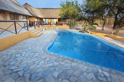 a swimming pool in a yard with a house at Normann Safari Bush Lodge in Phalaborwa