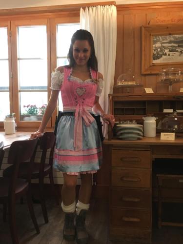 a young girl in a dress standing in a kitchen at Gasthaus Spinas in Bever