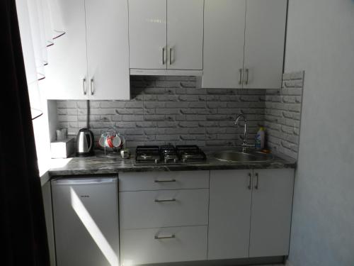 a kitchen with white cabinets and a sink at Apartment on Mstyslavs'ka in Chernihiv
