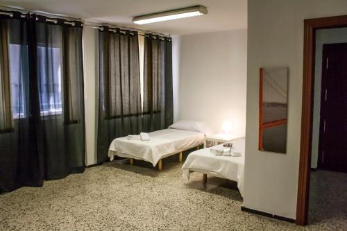 バレンシアにあるVivienda Amplia Mercado Central - Pie de La Cruzのベッド2台とテーブル2台が備わるホテルルームです。