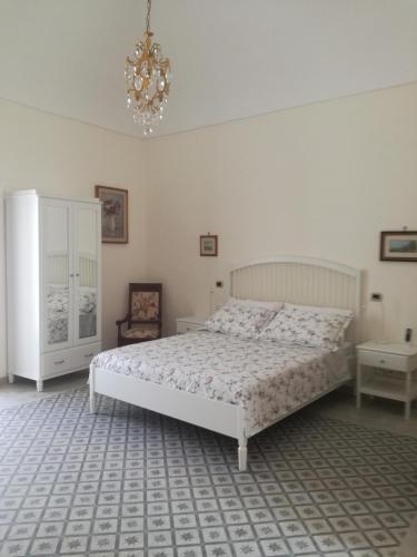 a white bedroom with a bed and a chandelier at B&B Stella in Vico Equense