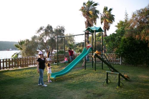 a woman and a child standing next to a playground at Greenport Bodrum Hotel in Guvercinlik