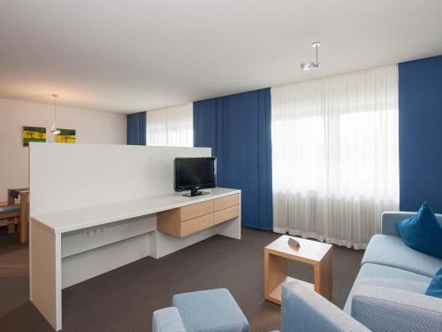 a living room with a white desk with a tv at Alpenresidenz Buchenhöhe in Berchtesgaden