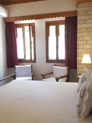 a bedroom with a bed and two chairs and windows at Hotel Gjirokastra in Gjirokastër
