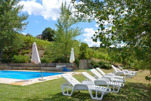 una fila di sedie a sdraio bianche accanto alla piscina di Poggio San Giacomo a Baschi