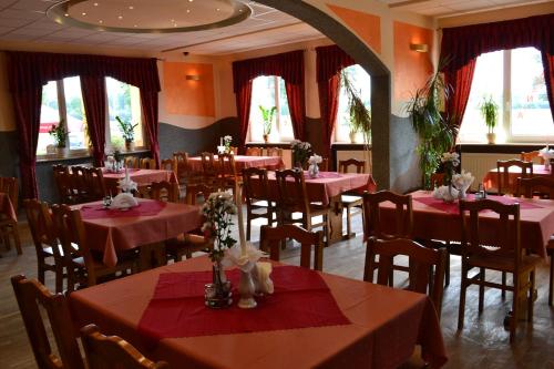 une salle à manger avec des tables rouges, des chaises et des fenêtres dans l'établissement Hotel i Restauracja Jaskolka, à Alojzów