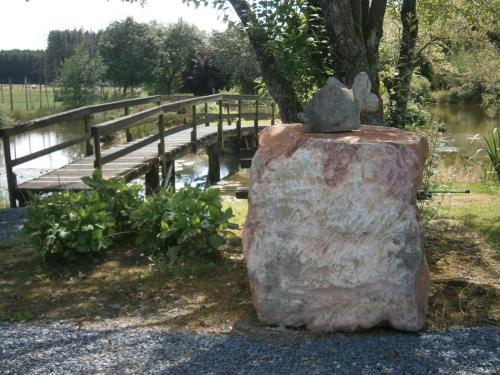 a statue of a cat sitting on a rock next to a bridge at Le Chalet Pré de la Fontaine in Paliseul