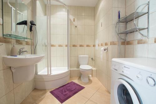 a bathroom with a toilet sink and a washing machine at Apartamenty Staromłyńska in Szczecin