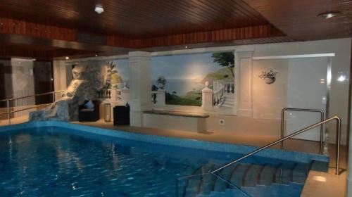 a swimming pool in a hotel with a mural of a building at Landhotel Spessartruh in Frammersbach