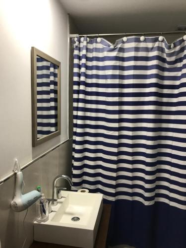 a bathroom with a sink and a shower curtain at Olivos Suites in Olivos