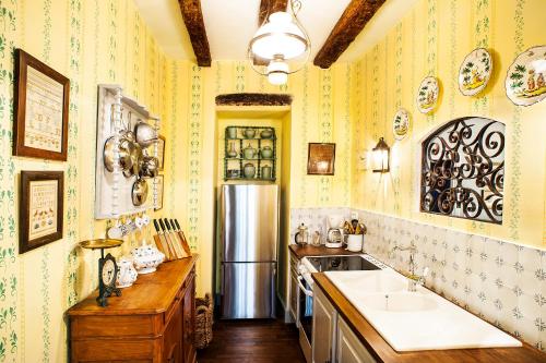 - une cuisine avec du papier peint jaune et un réfrigérateur dans l'établissement Appartements Les Suites sarladaises, à Sarlat-la-Canéda