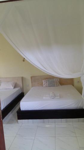 1 dormitorio con 2 camas con dosel en Amed Stop Inn Homestay, Rooftop Restaurant and Bar, en Amed