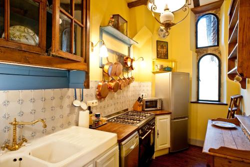 une cuisine avec des murs jaunes et une cuisinière et un évier dans l'établissement Appartements Les Suites sarladaises, à Sarlat-la-Canéda