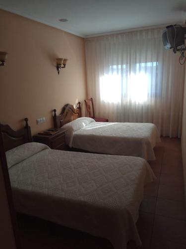 a hotel room with two beds and a window at Hostal Restaurante Raton in Paredes de Nava