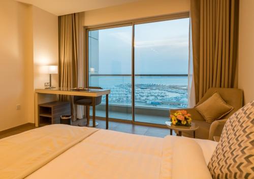 a hotel room with a bed and a desk and a window at Solymar Hotel & Beach in Manama