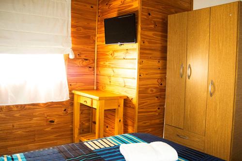 Un dormitorio con una cama, un escritorio y un televisor. en Las Vistas, en San Martín de los Andes