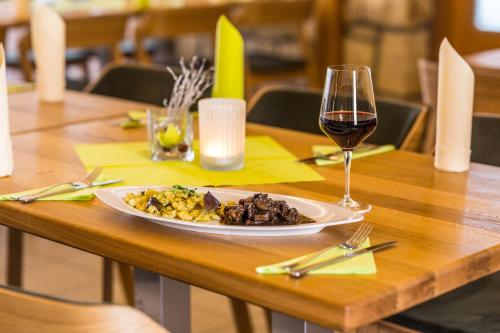 a plate of food and a glass of wine on a table at Hotel Kraví Hora in Bořetice
