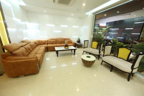 a living room with a brown couch and chairs at Hotel President in Nagpur