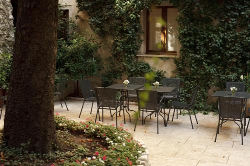 a patio with tables and chairs and a tree at Albergo Accademia in Trento